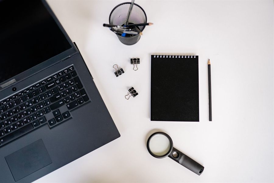 Laptop, notebook and magnifying glass on a desk